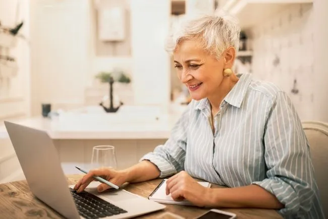 Frau am Laptop mit Stift in der Hand