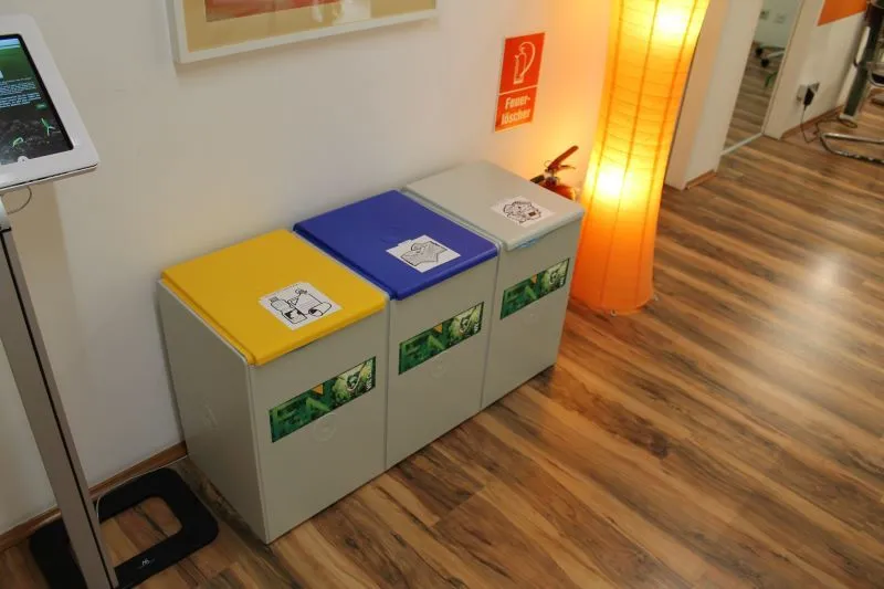 Mülltrennsystem im FUN. Drei Container mit unterschiedlich farbigen Deckeln.