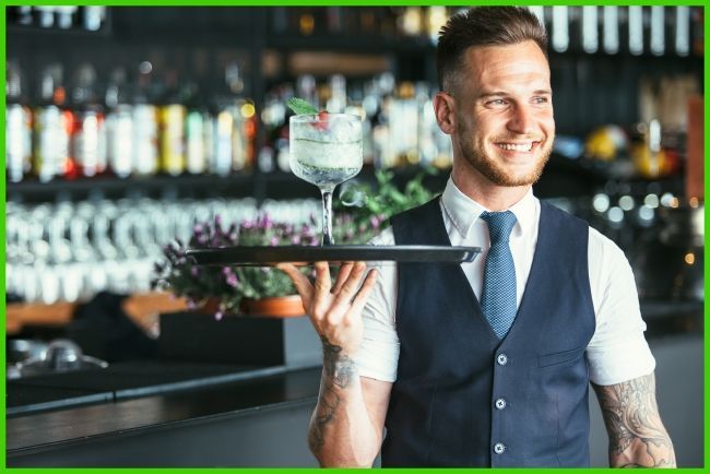 Kellner mit Tablett mit Glas in der rechten Hand