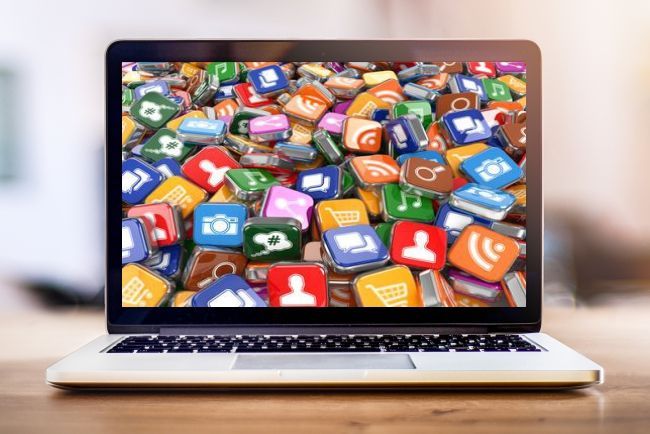 Laptop mit kleinen bunten social media Icons am Bildschirm