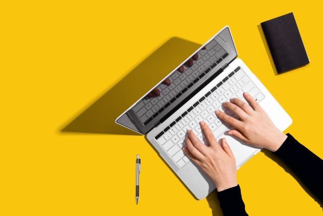 Laptop mit zwei Händen auf Tastatur
