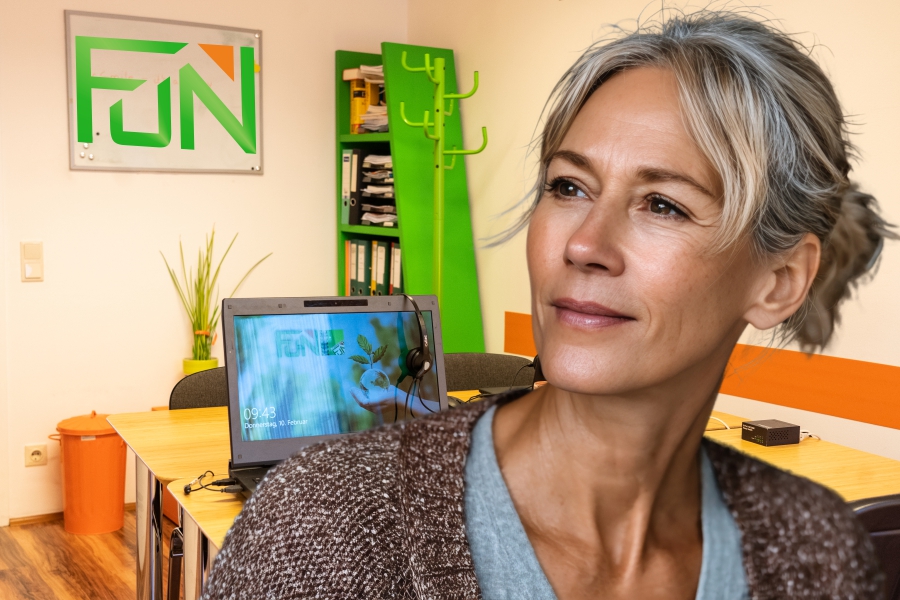 Frau mit grau, blonden Haar- Im Hintergrund ein Schulungsraum im FUN